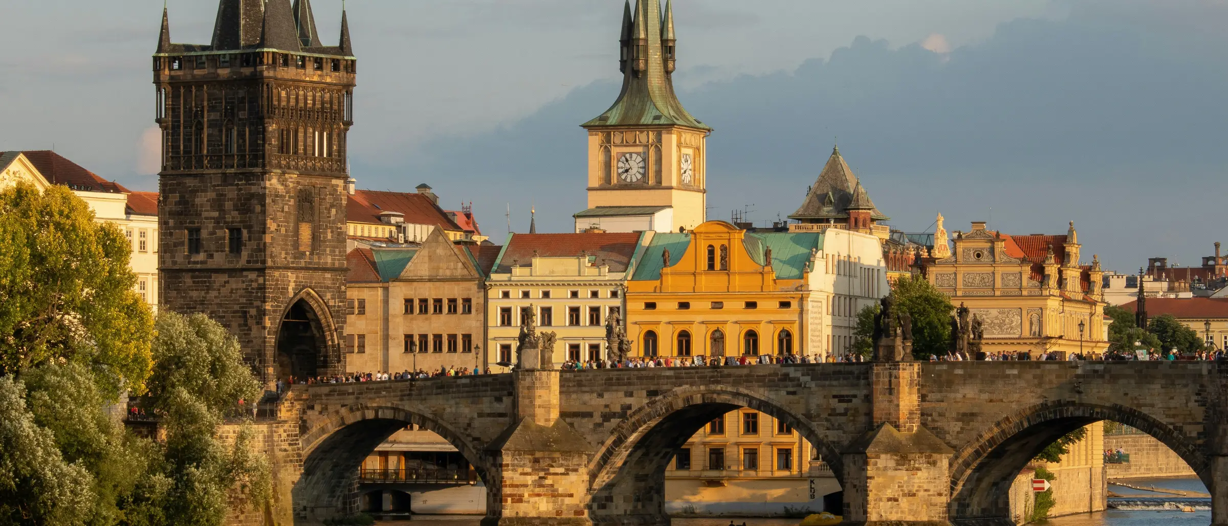 Le pont Charles et la tour du pont de la Vieille Ville en lumière dorée, vus depuis la Vltava.