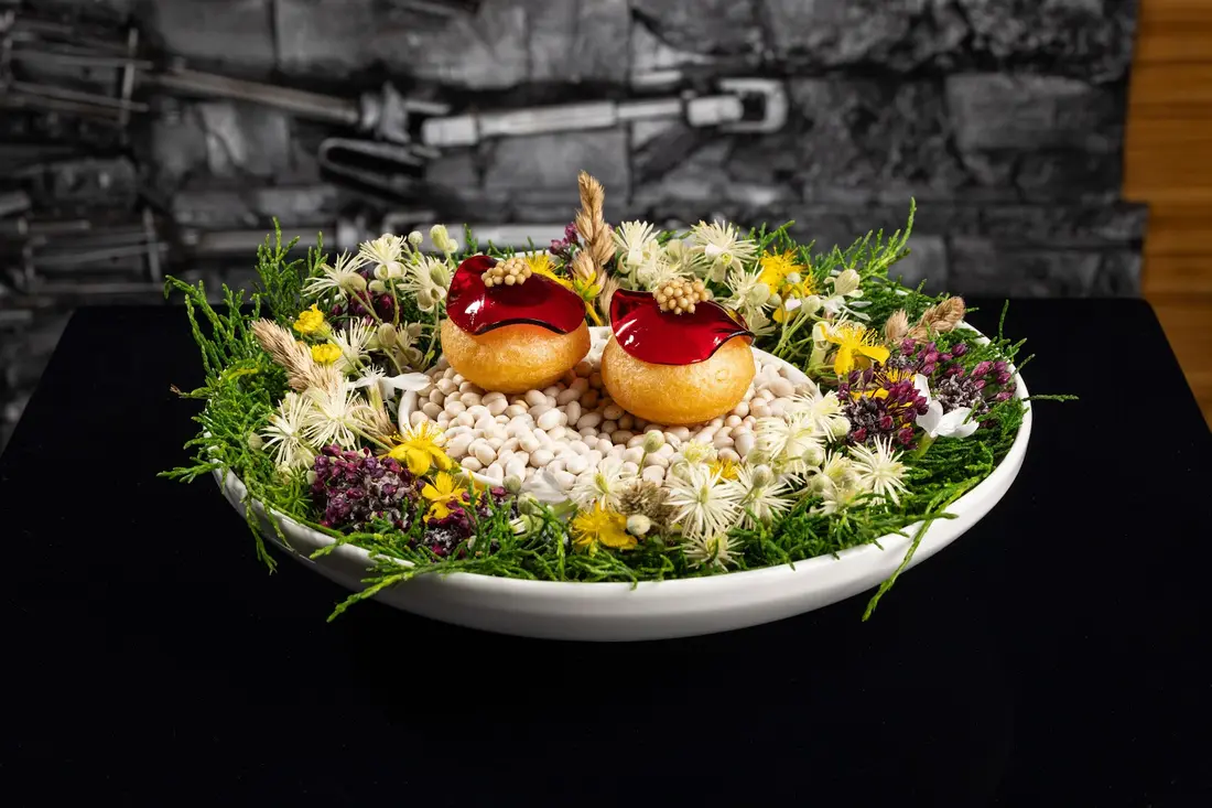 Assiette dressée sur un lit de fleurs et d’herbes.