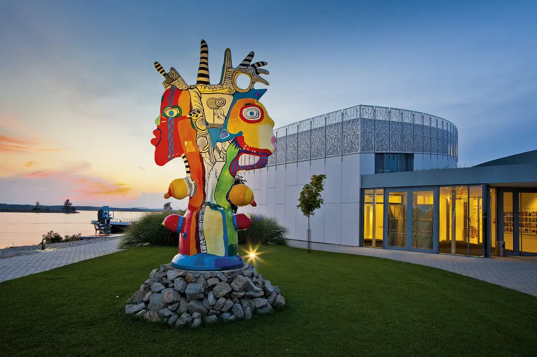 Le musée Danubiana sur le Danube et sa sculpture monumentale, au crépuscule.